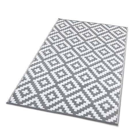 Tapis d’extérieur réversible gris et blanc à motif géométrique posé sur une terrasse en bois