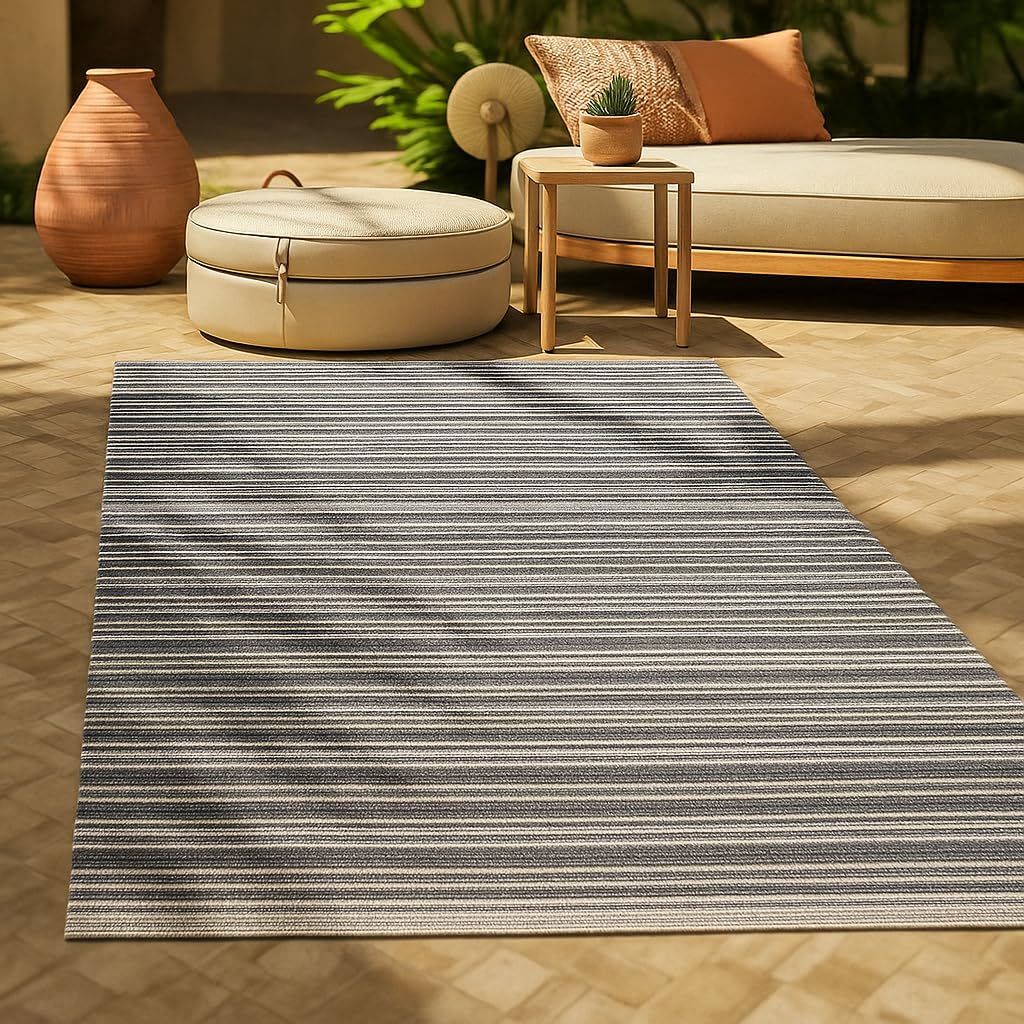Tapis d’extérieur réversible à rayures anthracite et blanches posé sur une terrasse claire