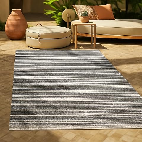 Tapis d’extérieur réversible à rayures anthracite et blanches posé sur une terrasse claire
