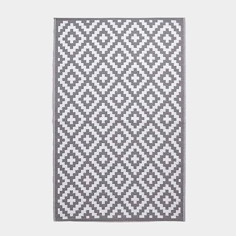 Tapis extérieur réversible gris et blanc à motif géométrique posé sur une terrasse après la pluie