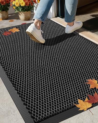 Paillasson extérieur géométrique noir et gris posé sur une terrasse en pierre après la pluie
