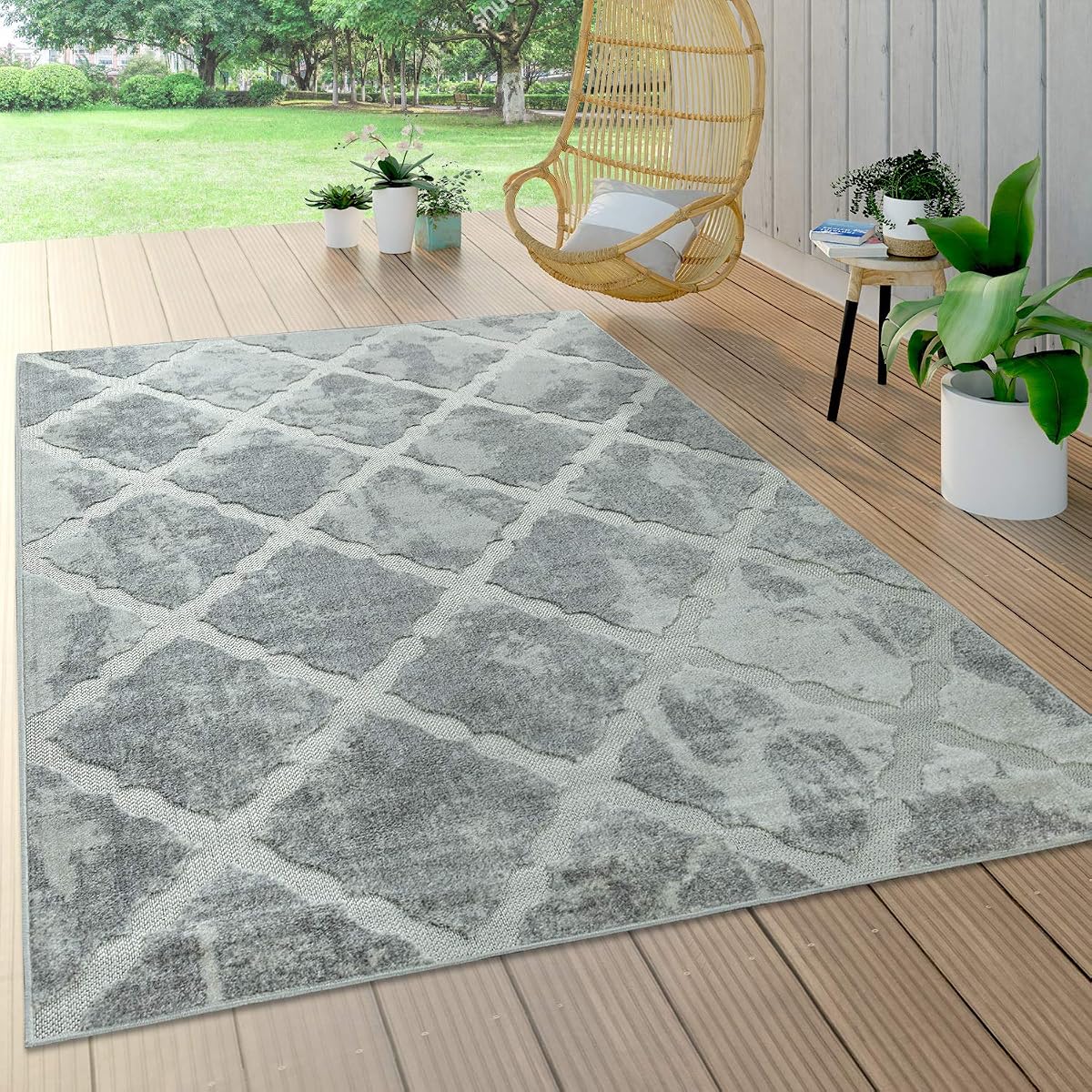 Tapis rectangulaire gris à motif géométrique posé sur une terrasse en bois après la pluie