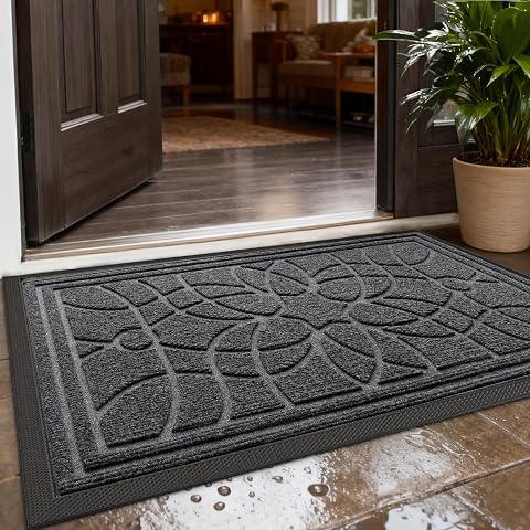 Paillasson gris foncé à motif floral en relief posé sur une terrasse après la pluie