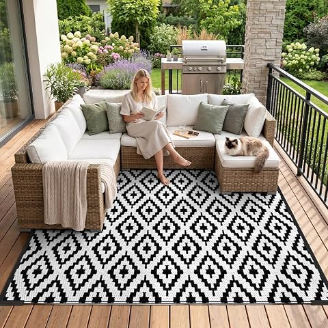 Tapis d’extérieur réversible à motif géométrique noir et écru posé sur une terrasse en bois après la pluie
