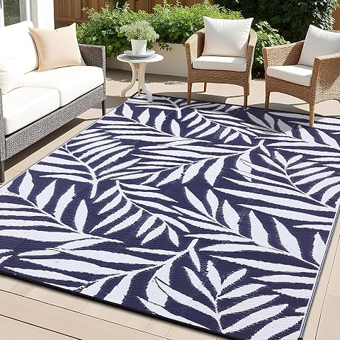 Tapis d’extérieur réversible bleu marine et blanc à motif de feuilles sur une terrasse en bois