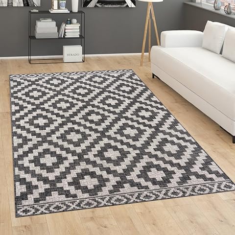 Tapis anthracite à motif géométrique posé sur une terrasse en bois après la pluie.