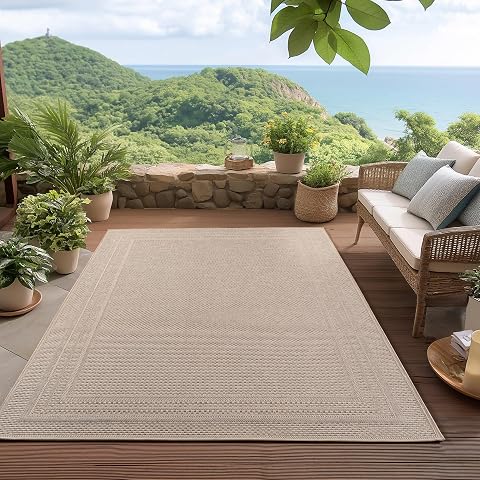 Tapis d’extérieur beige à tissage plat et bordure posé sur une terrasse en bois après la pluie