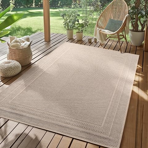 Tapis beige rectangulaire à motif cadre posé sur une terrasse en bois après la pluie.