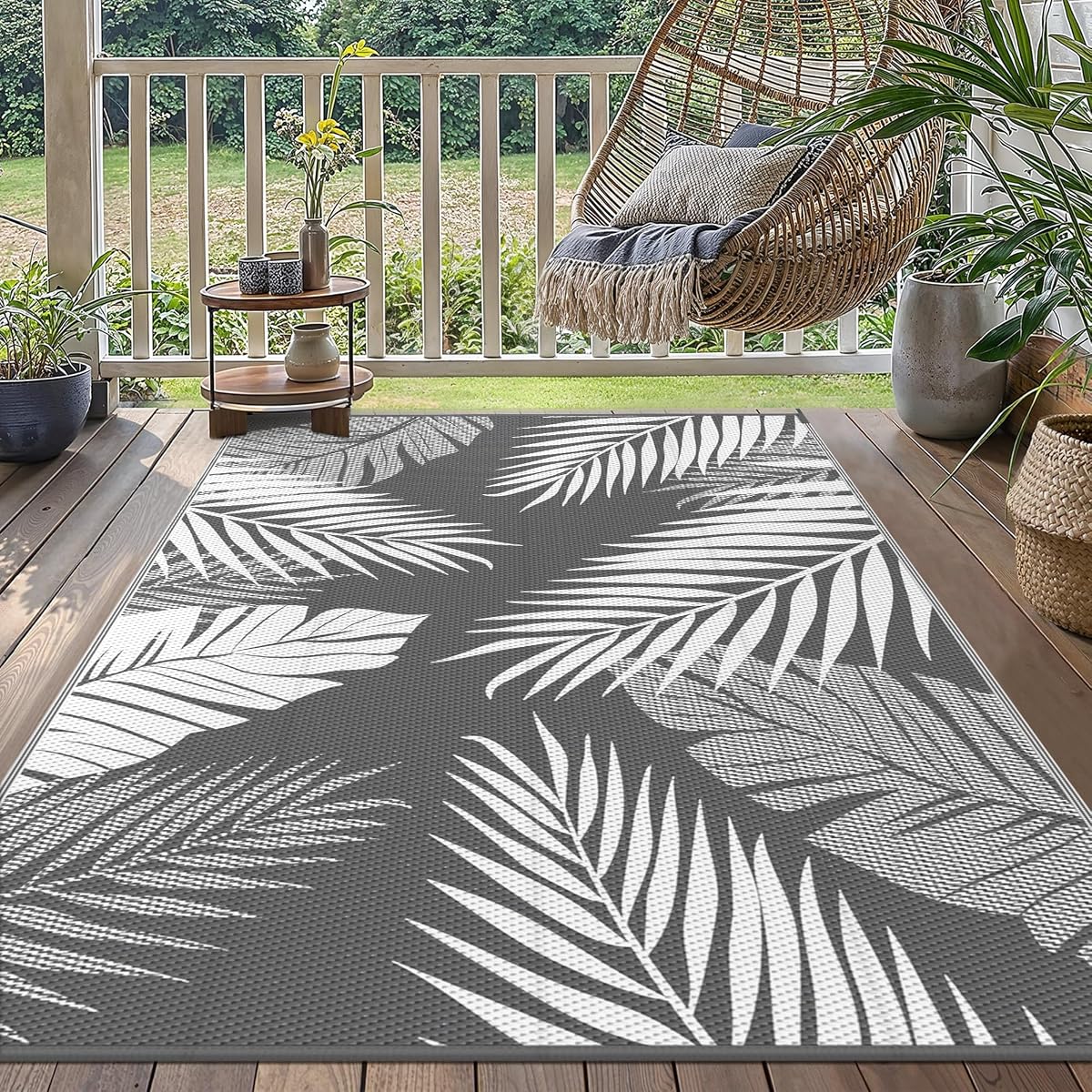 Tapis extérieur réversible à motif de feuilles gris et blanc posé sur une terrasse en bois