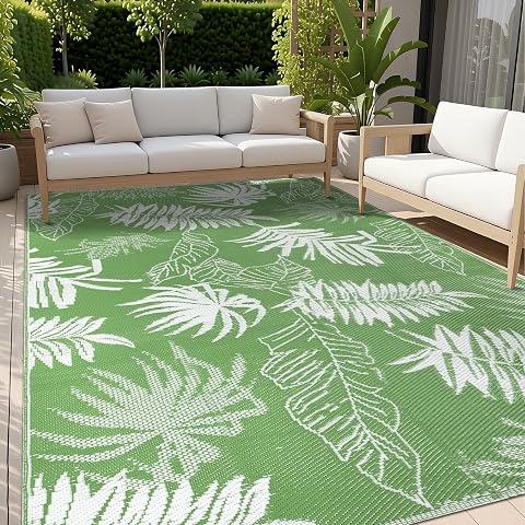 Tapis extérieur vert à motif de feuilles de palmier déployé sur une terrasse en bois après la pluie