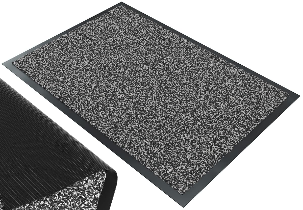 Paillasson rectangulaire gris-noir posé devant une entrée sur une terrasse après la pluie