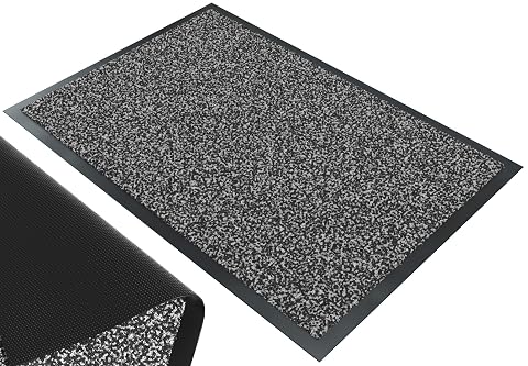 Paillasson rectangulaire gris-noir posé devant une entrée sur une terrasse après la pluie