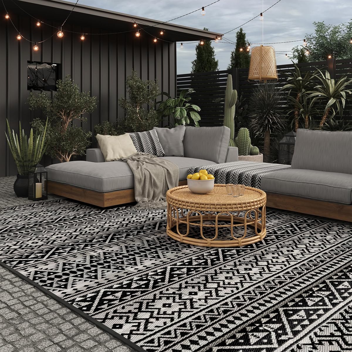 Tapis extérieur géométrique noir et blanc déployé sur une terrasse en pierre après la pluie