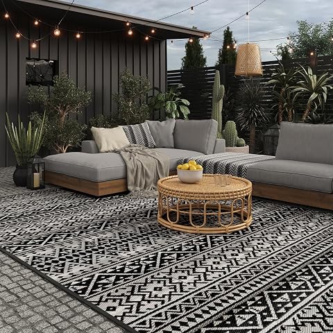 Tapis extérieur géométrique noir et blanc déployé sur une terrasse en pierre après la pluie