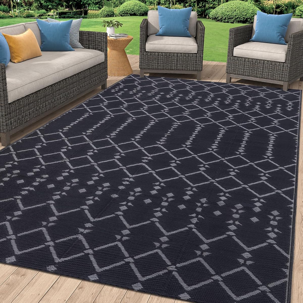 Tapis d’extérieur réversible gris foncé à motif géométrique posé sur une terrasse en pierre après la pluie.